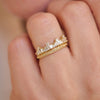 Woman wearing 14k yellow gold and baguette diamond tiara engagement ring stacked with a wind spiral wedding band.