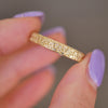 Woman holding unisex vintage-inspired 14k yellow gold antique star wedding band.