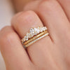 Woman wearing diamond marquise and pear engagement ring with stacked floral-engraved band, and pave diamond band.