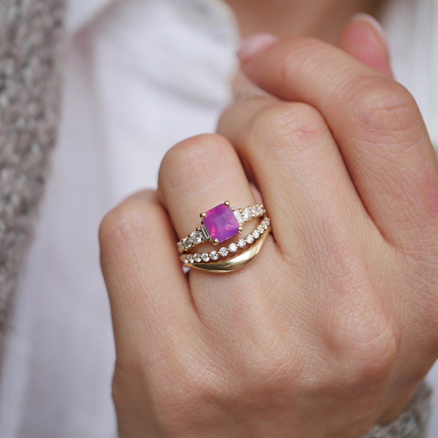 This elegant ring features an 
unheated cushion cut opalescent ruby-colored sapphire, beautifully surrounded by eight natural diamonds in round, carré, and baguette cuts, offering a timeless design with exceptional sparkle and color.