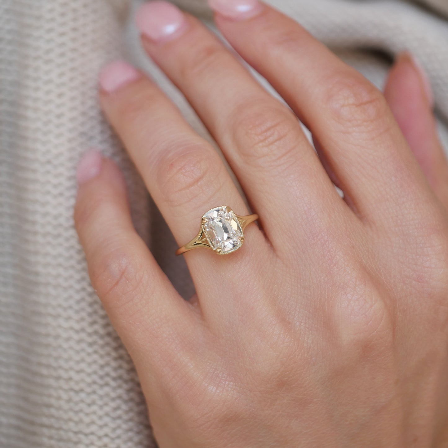 A dazzling cushion cut diamond takes center stage in this ring, framed by a unique split shank band for a striking visual appeal.