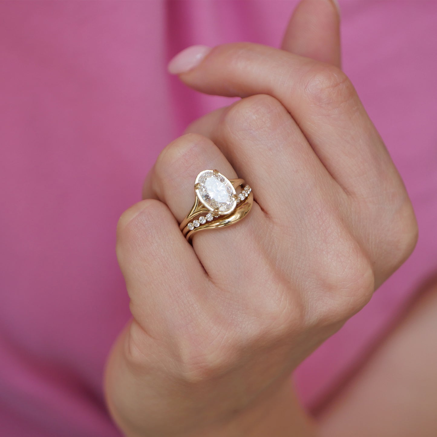 A stunning split shank engagement ring features oval brilliant cut diamonds, paired with matching curved diamond contour bands that wrap around the center stones for a sleek and luxurious finish.