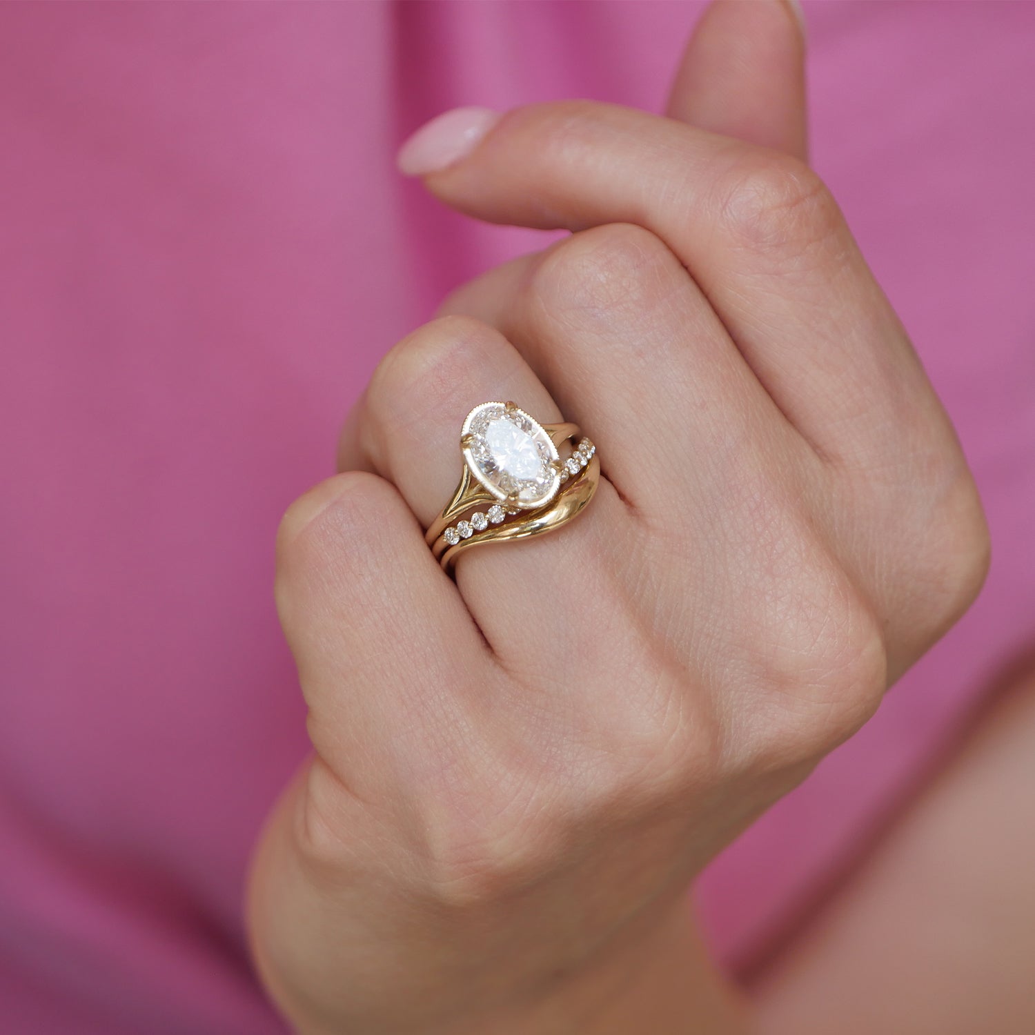 A stunning split shank engagement ring features oval brilliant cut diamonds, paired with matching curved diamond contour bands that wrap around the center stones for a sleek and luxurious finish.
