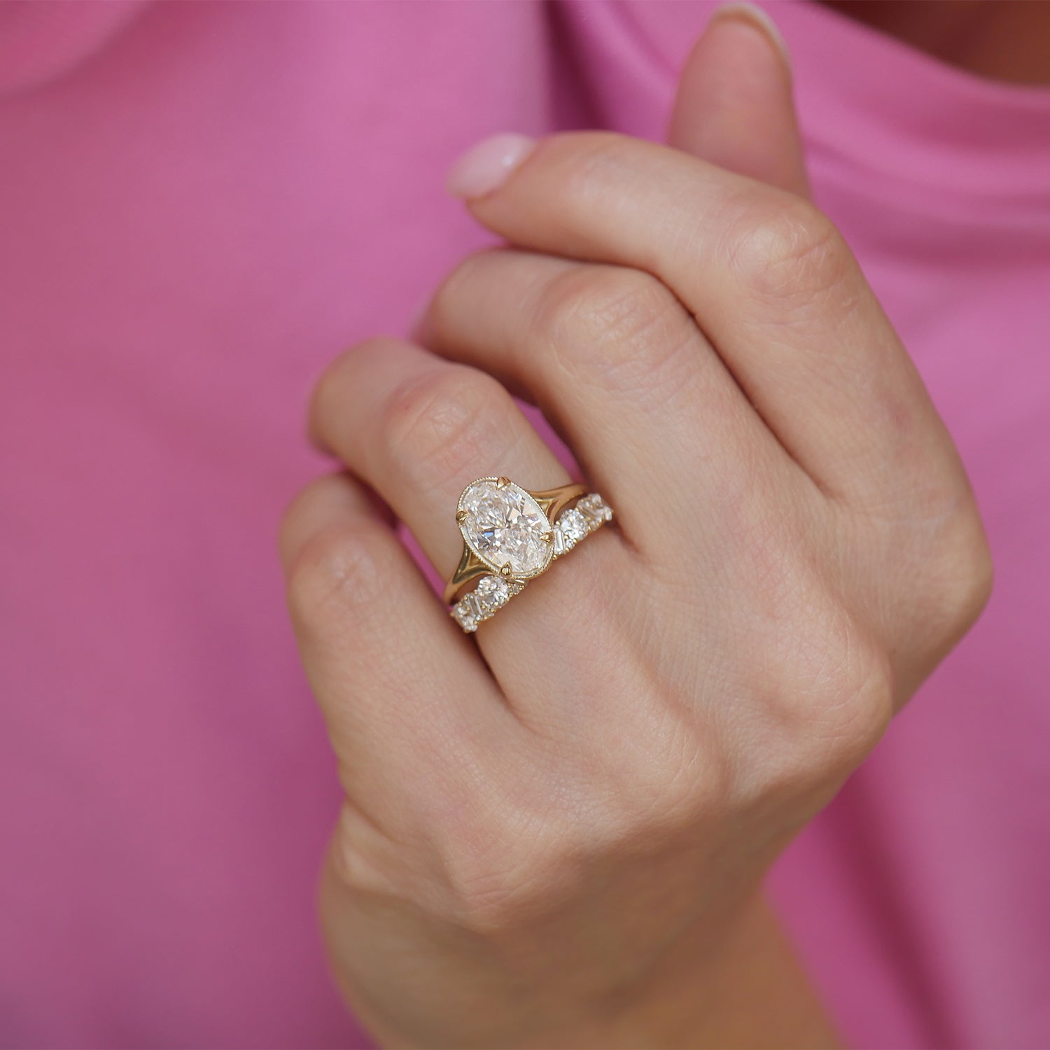 This split shank engagement ring, designed with oval brilliant cut diamonds, is paired with perfectly contoured diamond wedding bands, creating an exquisite and refined bridal set full of elegance and sparkle.