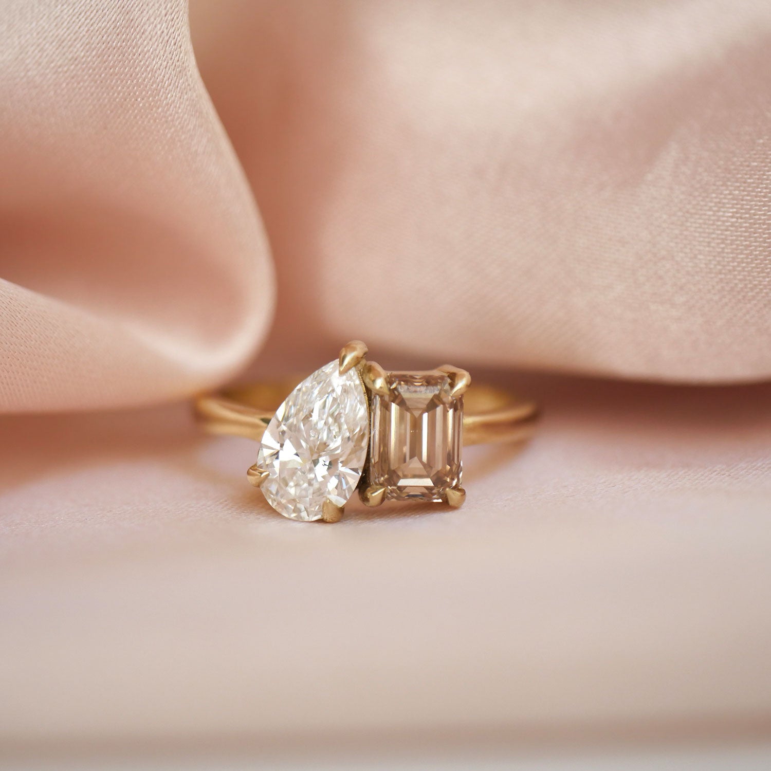 This exquisite ring pairs a sparkling pear diamond with a warm champagne emerald, offering a unique and elegant take on the traditional toi et moi design, perfect for an unforgettable romantic gesture.