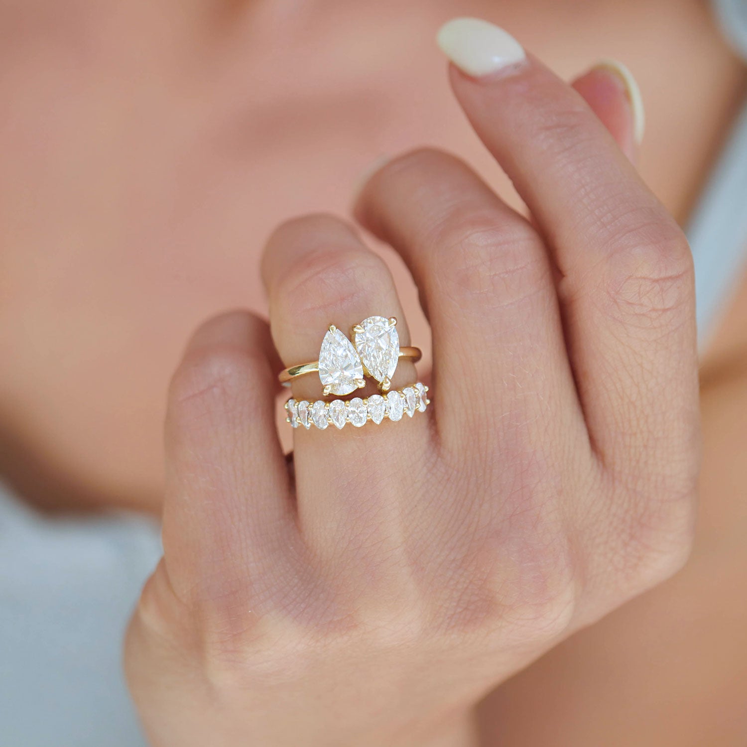 This ring featuring two pear-shaped diamonds, serves as a beautiful reminder of the shared journey between two people, with each diamond representing their individual beauty and togetherness. Stacked with a diamond wedding band.